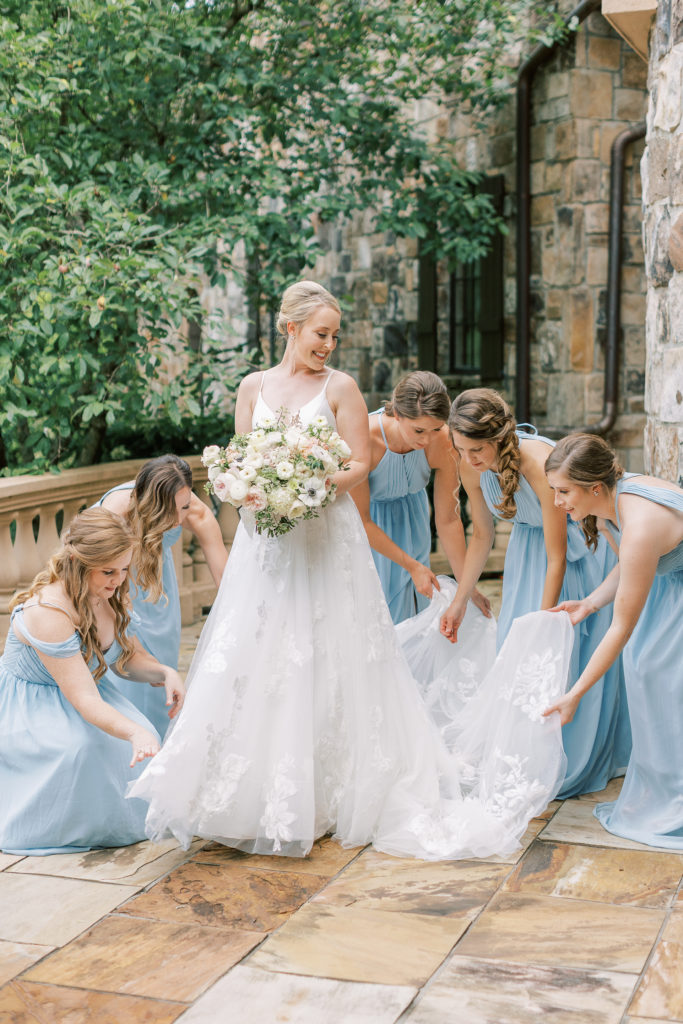 bridesmaids help adjust bride's wedding gown train
