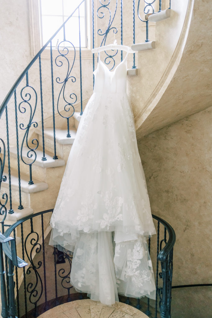 bridal gown hangs on grand staircase at estate wedding