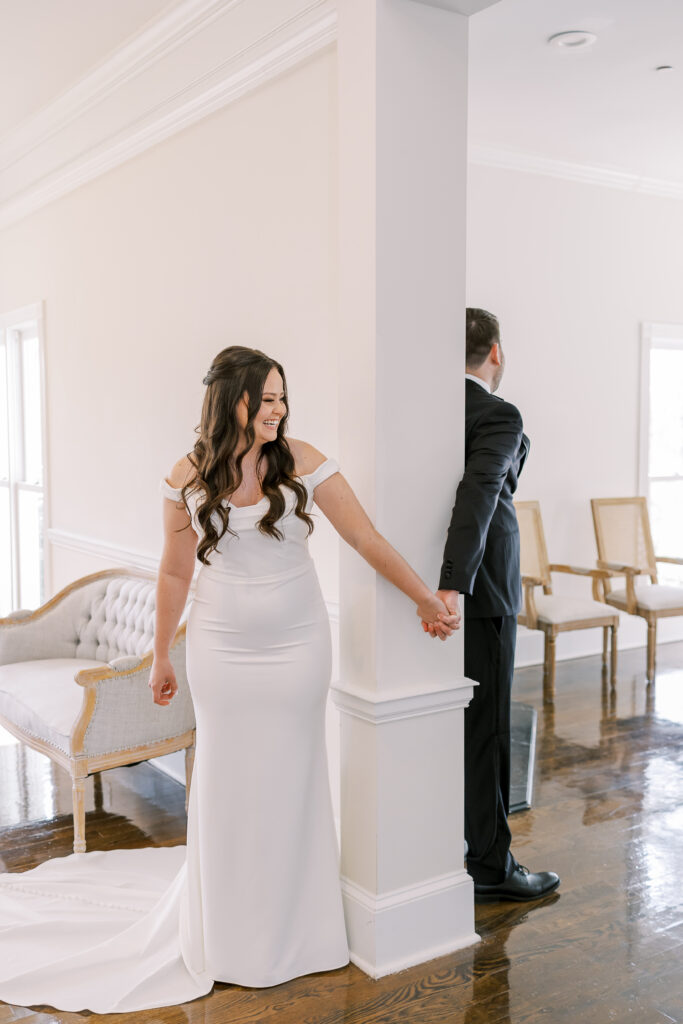 bride and groom holding hands around doorway