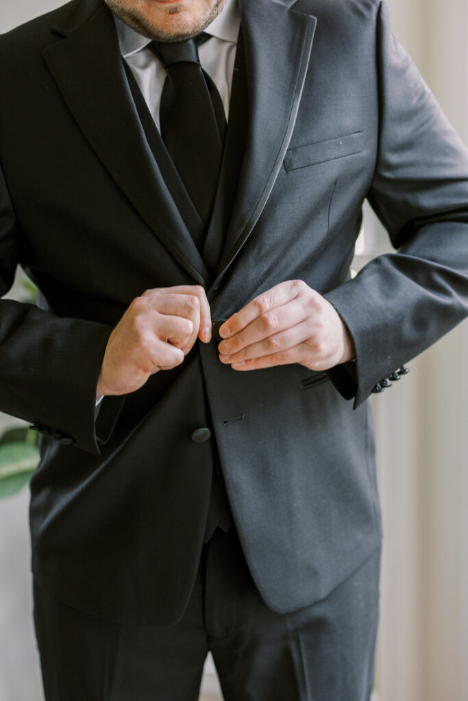 a groom buttoning his coat