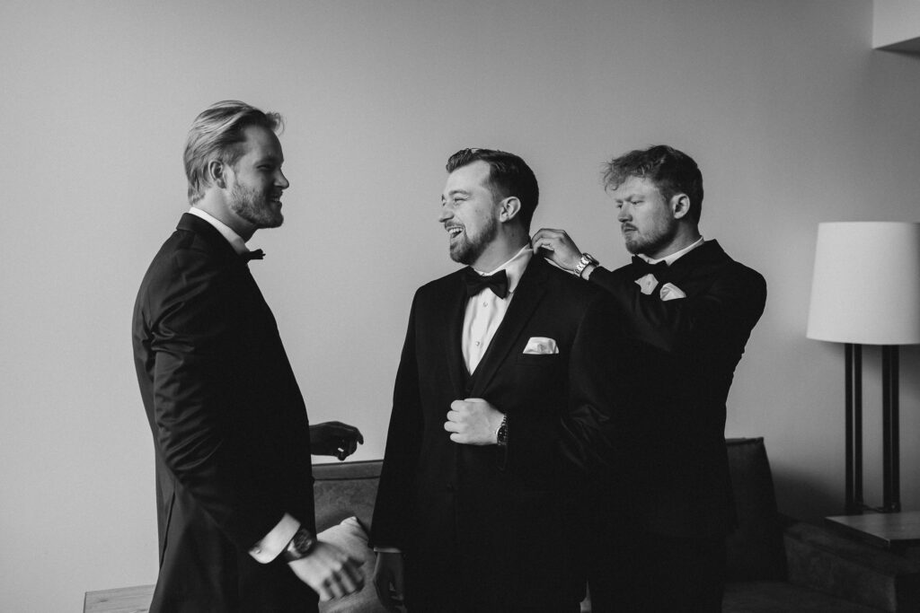 groomsmen helping the groom get dressed