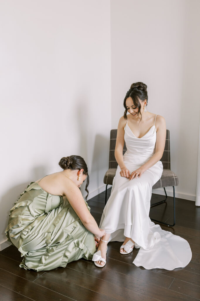 bridesmaid helping bride put on her high heels