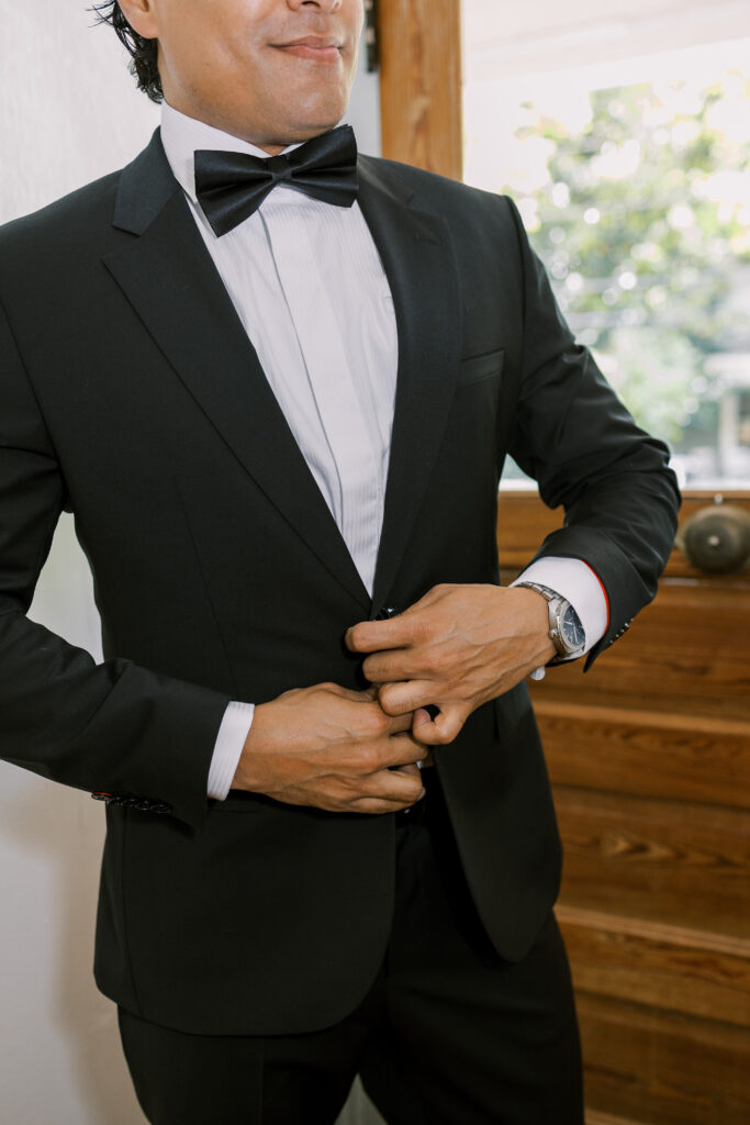 groom putting on his tuxedo