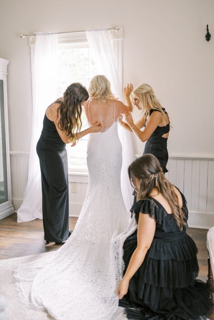 bridesmaids helping bride into her dress