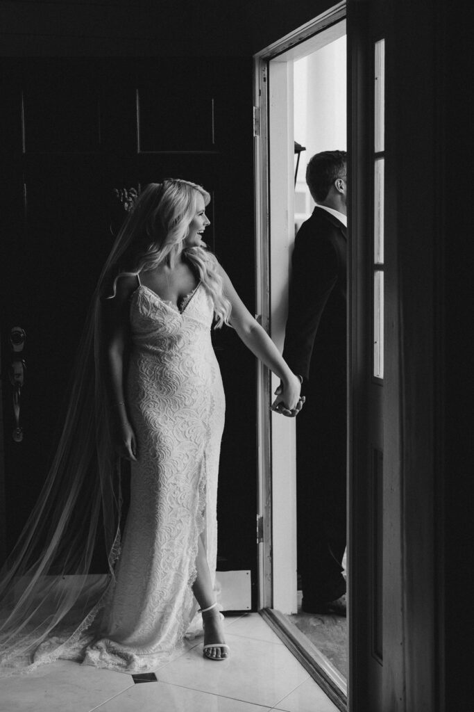 bride and groom holding hands around a door