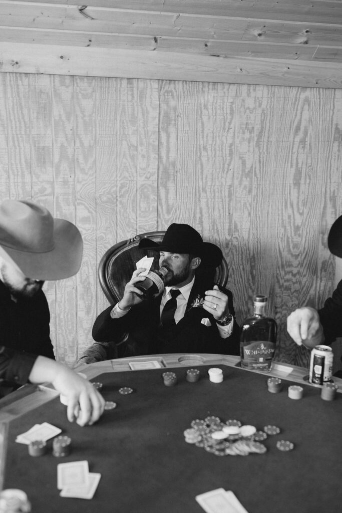 portrait of the groom playing poker with his groomsmen and drinking bourbon