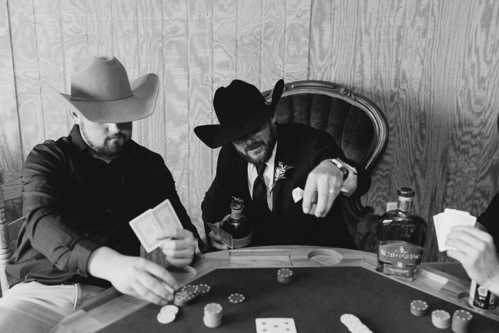 portrait of the groom playing poker with his groomsmen and drinking bourbon