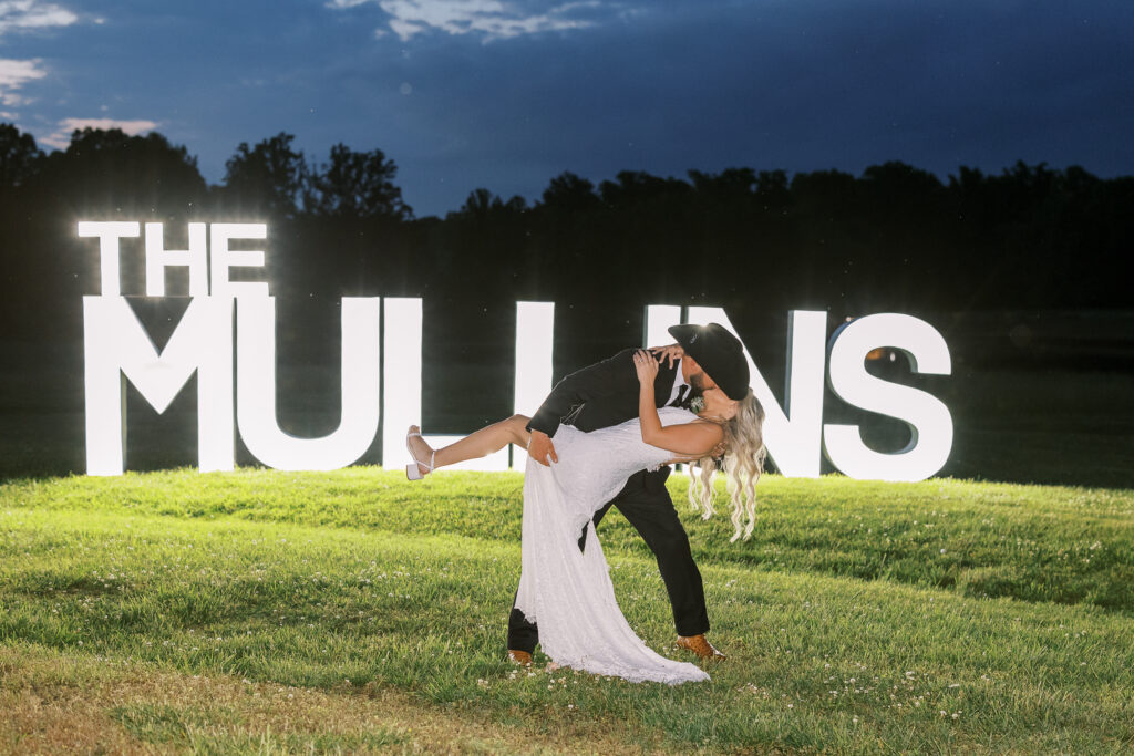 bride and groom kissing in front of a sign of their new last name