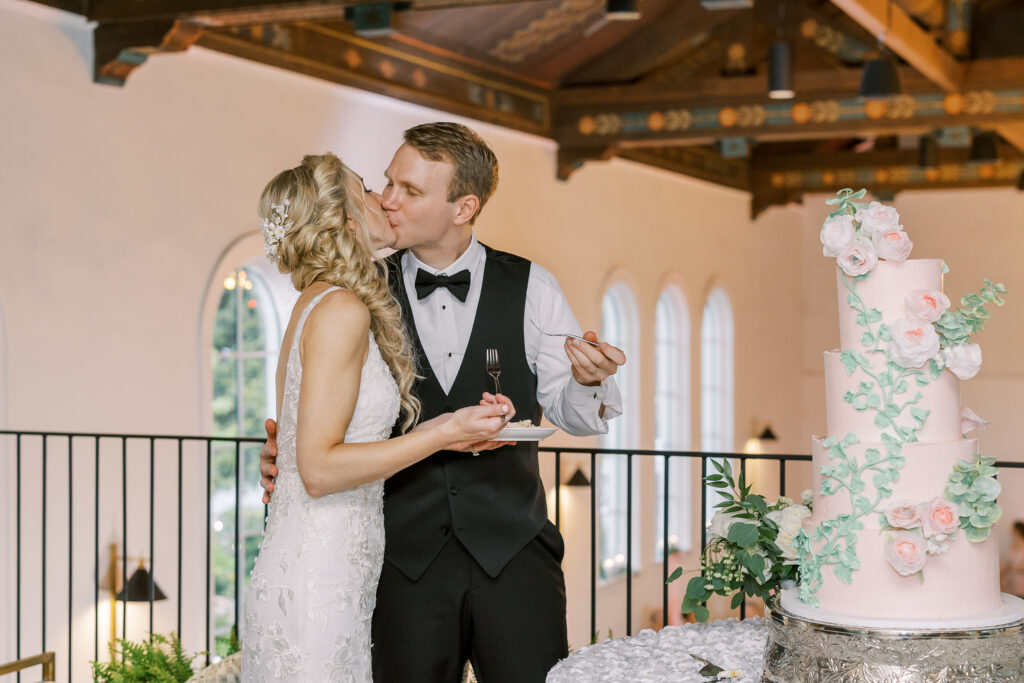 bride and groom kissing in front of the cake