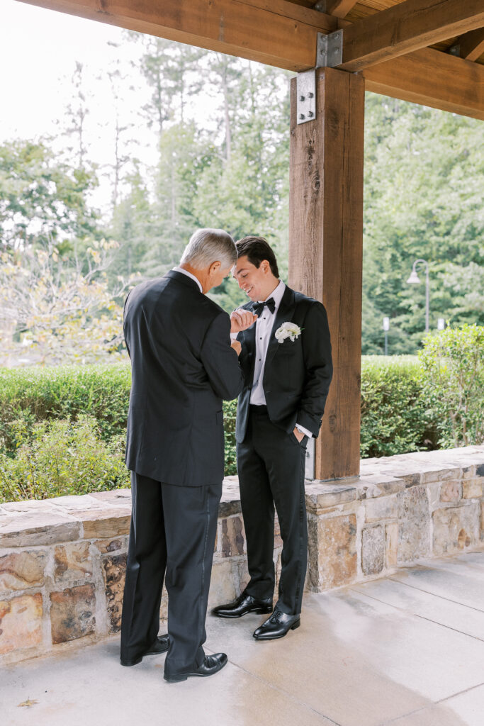 father of the groom helping groom put on cuff links