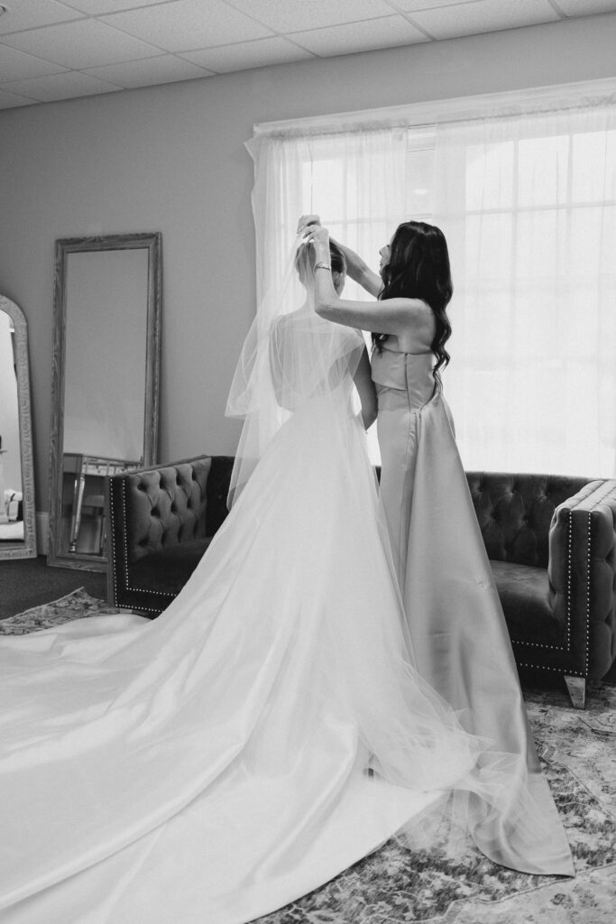 bridesmaid helping bride put on her veil