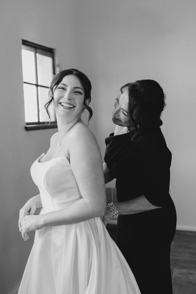 bride and her mom putting on the dress