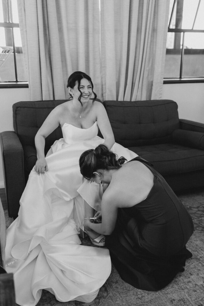 bridesmaid putting on the bride's shoe