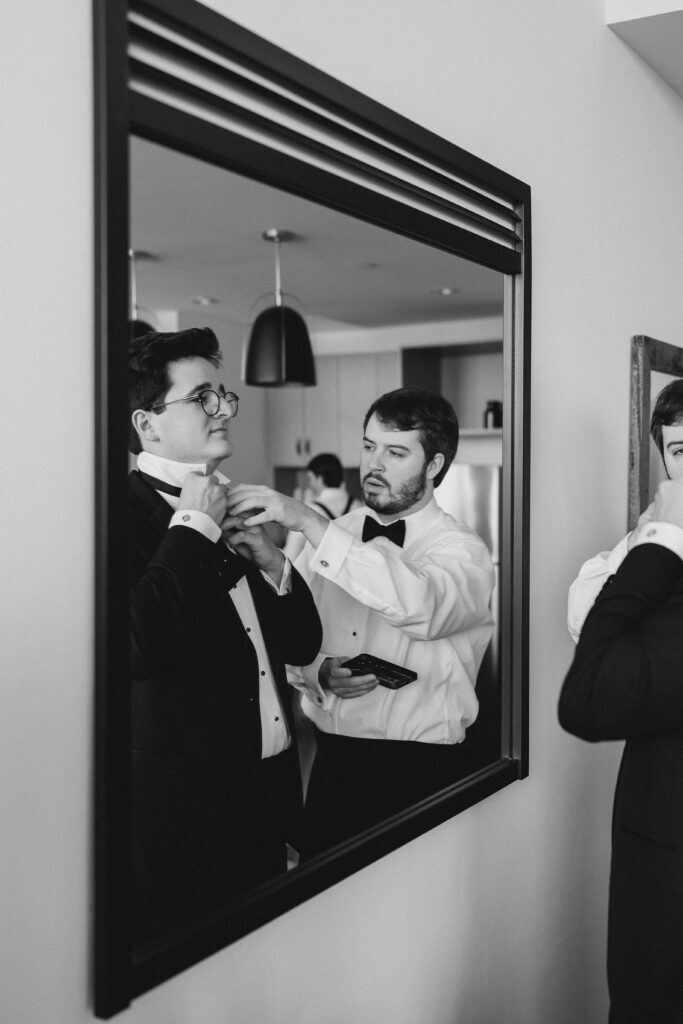 groomsmen helping the groom tie a bowtie