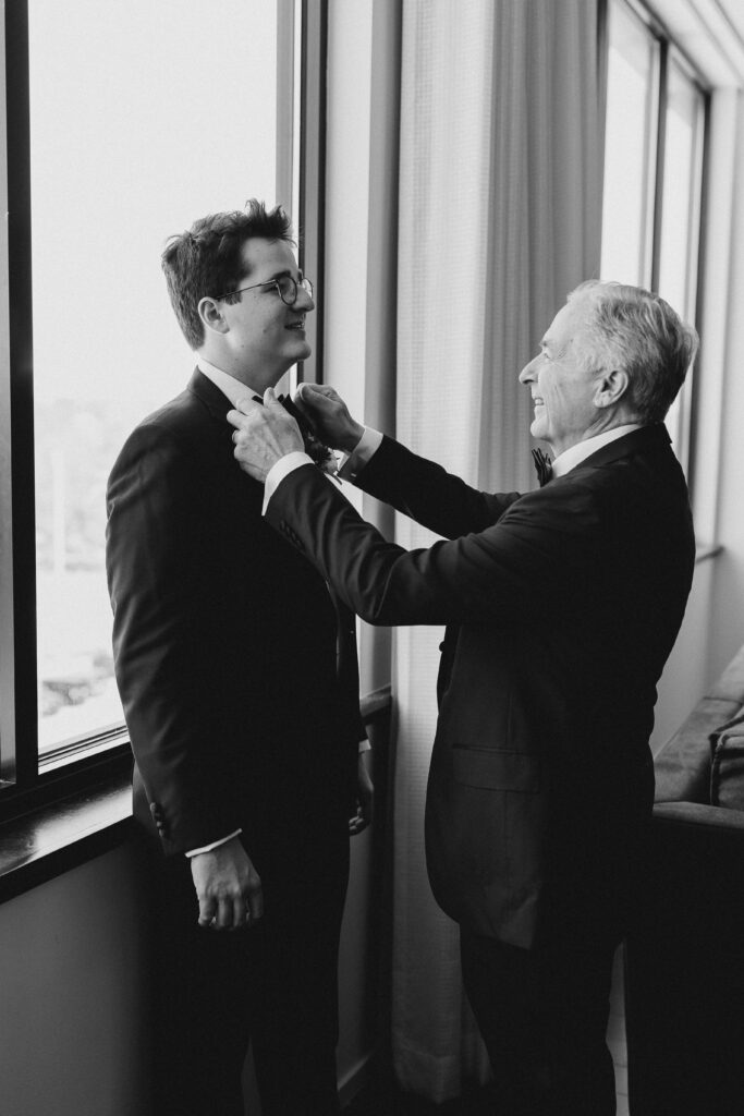 groom's father helping groom tie a bowtie