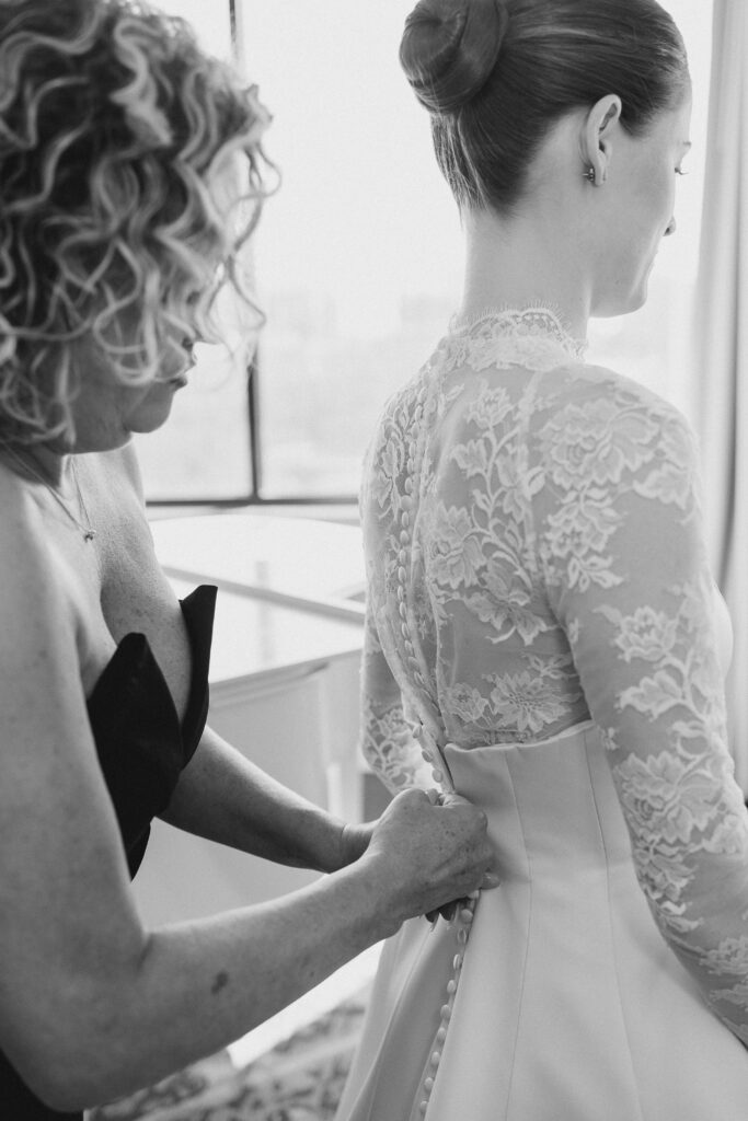 bride's mother helping her put on her wedding dress