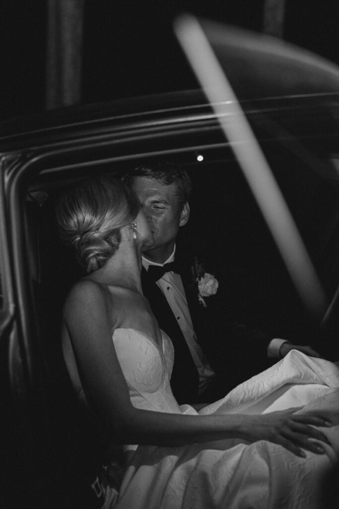 bride and groom kissing in a car