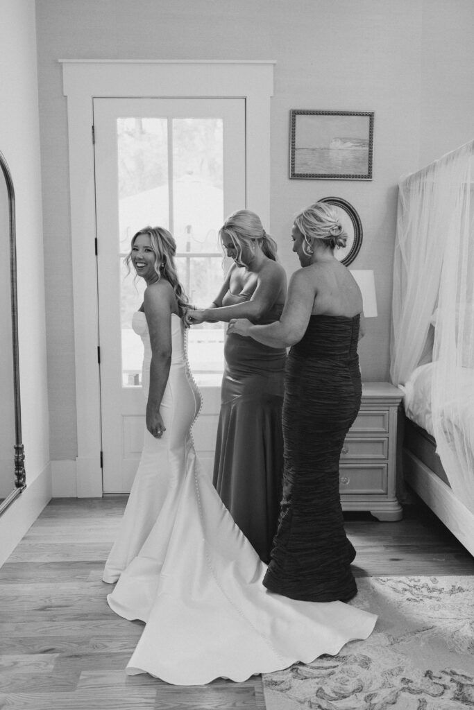 bridesmaid helping bride into dress