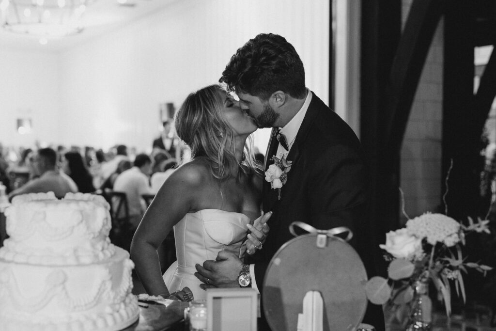 bride and groom kissing by the cake
