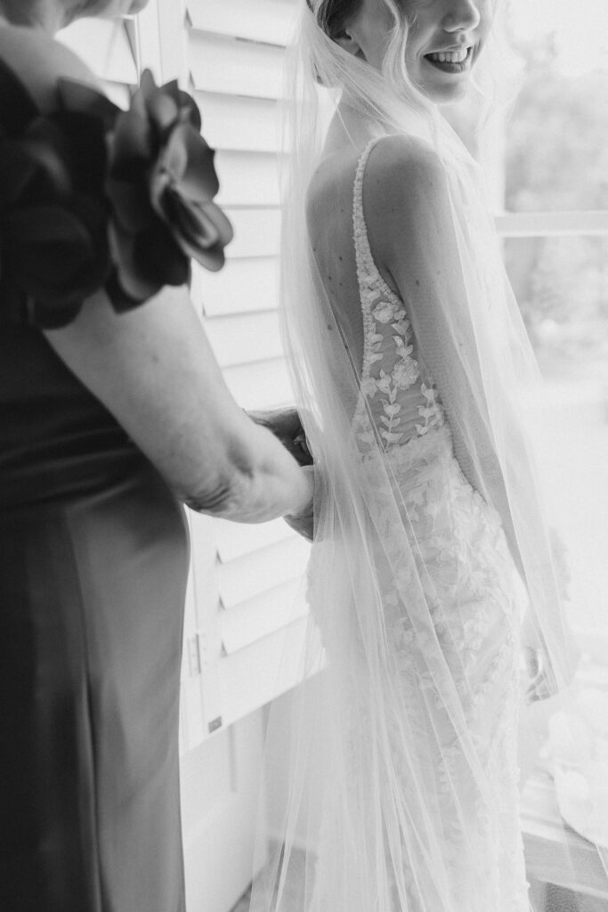 bride's mom helping her into wedding dress