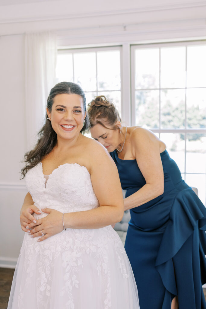 mother of the bride helping the bride put on her dress