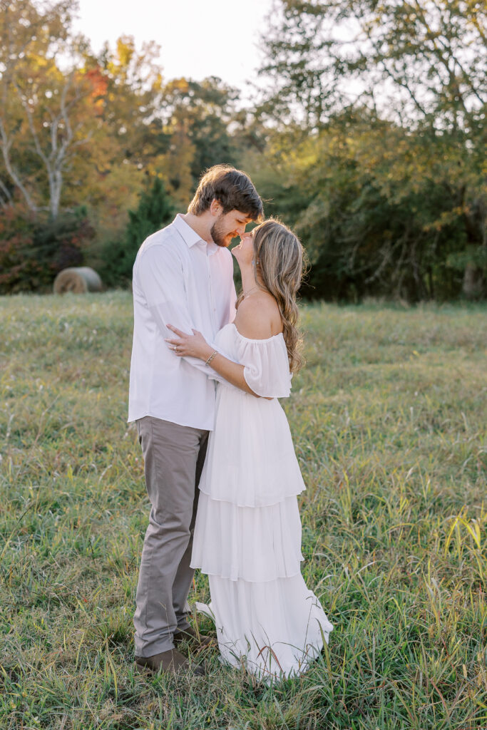a couple having an engagement photography session in a field during golden hour