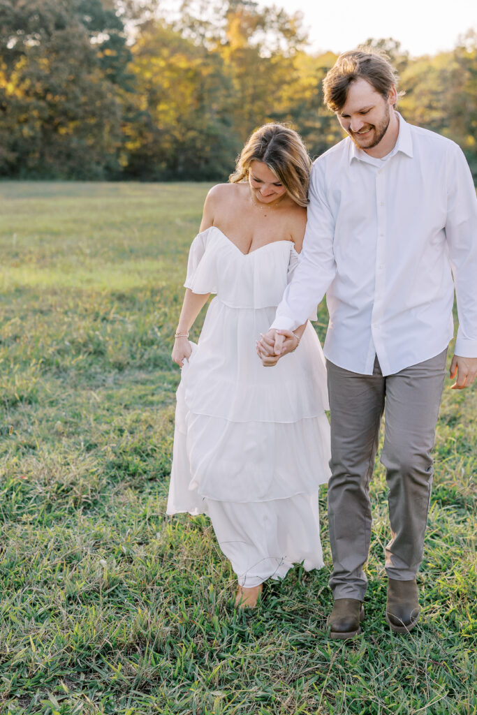 a couple having an engagement photography session in a field during golden hour
