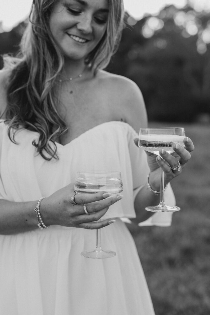 a couple having an engagement photography session in a field during golden hour with champagne