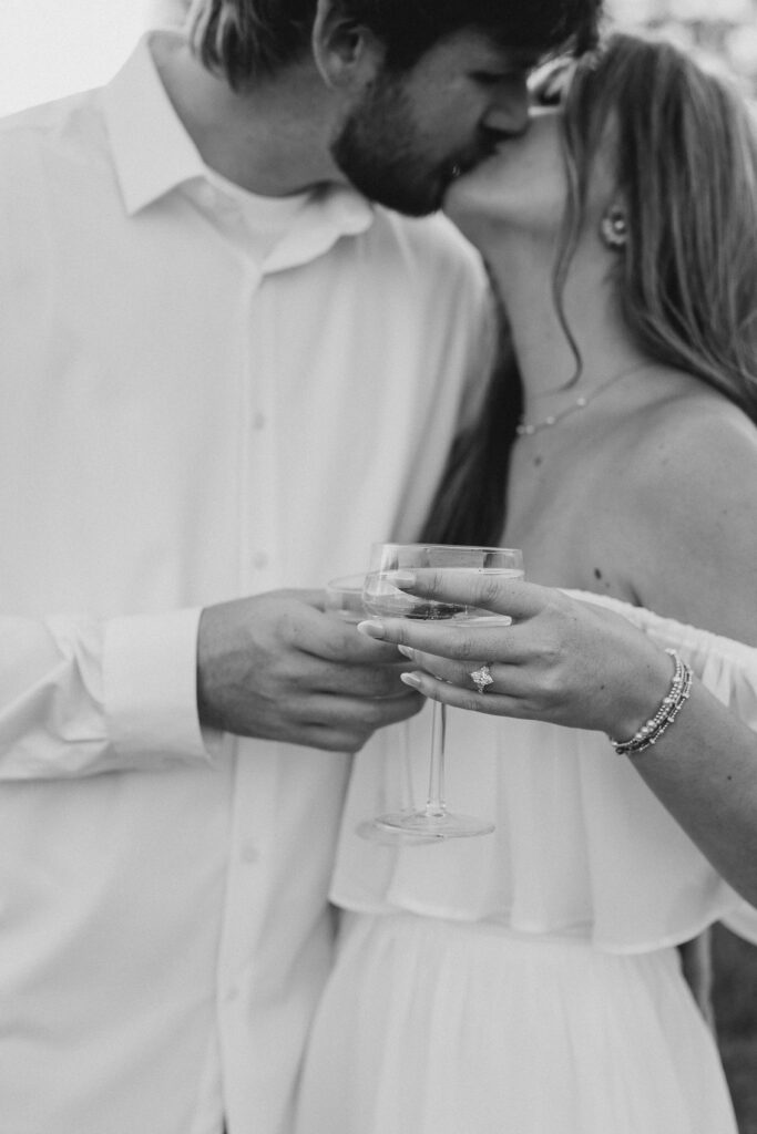 a couple having an engagement photography session in a field during golden hour with champagne
