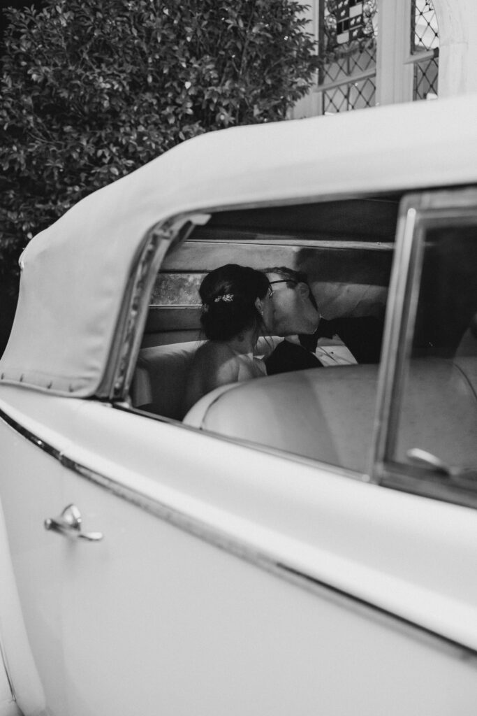 bride and groom kissing in a car