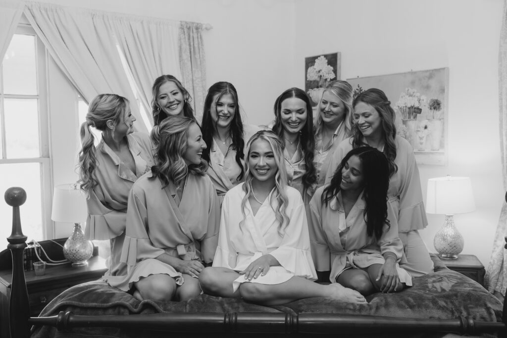 bride and her bridesmaids getting ready on a bed